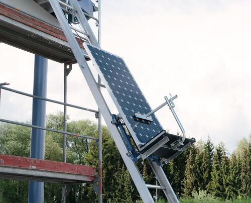 Solarlift i användning. Transporterar solpaneler upp till ett tak.
