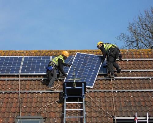 GEDA Solarlift uppe på ett tak. Två arbetare lyfter av en solpanel från liftens flak.